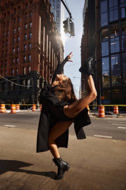 Siyah ceketli genç bir kadın New York sokaklarında dans ediyor..