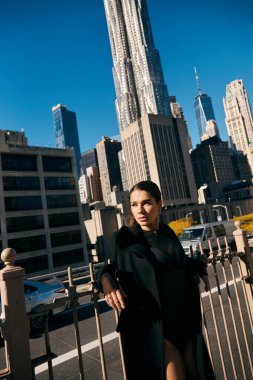 Genç bir kadın New York 'ta bir caddede duruyor, bakışları uzak şehir manzarasına kilitlenmiş..