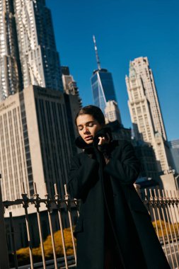 A young woman stands in a New York City street, shrouded in shadow. clipart