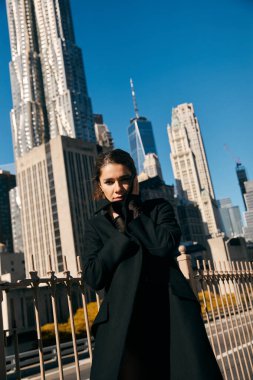 Siyah ceketli genç bir kadın New York caddesinde duruyor..