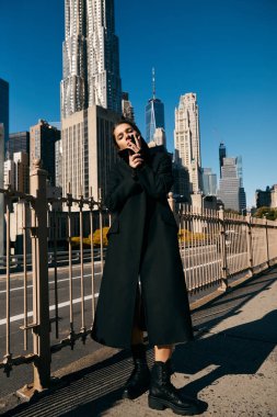 Siyah ceketli kadın New York caddesinde gökdelenlerin ortasında dans ediyor..