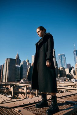 New York 'ta bir köprüde dans eden bir kadın. Arkasında Manhattan silueti olan..