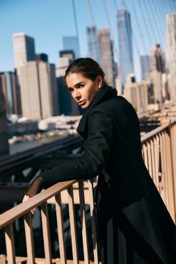 Genç bir kadın New York 'ta bir köprüde durup manzaranın tadını çıkarıyor..