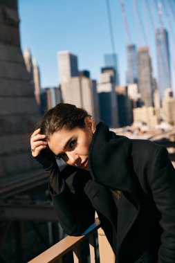 Siyah ceketli genç bir kadın New York 'ta korkuluklara yaslanıyor..