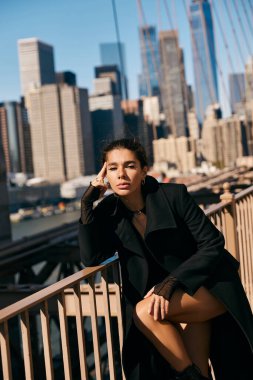 New York 'ta bir korkulukta oturan genç bir kadın, bu hareketli şehrin ortasında düşüncelere dalmış..