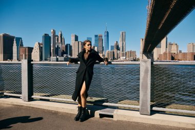 New York 'ta bir köprüde dans eden genç bir kadın, arka plandaki şehir manzarası....