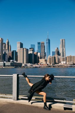 New York 'ta bir rıhtımda dans eden genç bir kadın. Arka planda ikonik bir siluet var..