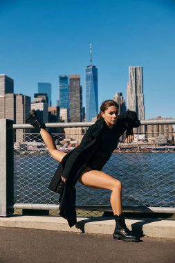 New York 'ta bir köprüde dans eden genç bir kadın silueti şehrin silueti tarafından çerçevelenmiş..