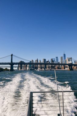 New York şehrinin manzarası sudan ufuk çizgisi, ön planda bir köprü..