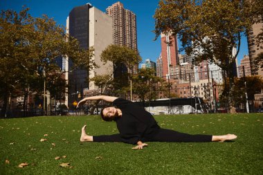 A young woman stretches in a New York park, surrounded by tall buildings. clipart