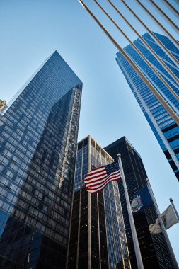 New York 'taki gökdelenlerin alçak açılı görüntüsü Amerikan bayrağı rüzgarda dalgalanırken.