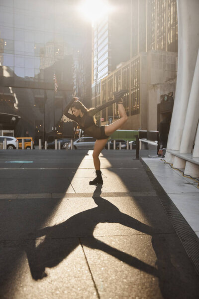 A young woman dances on the streets of New York City in the morning sunlight.