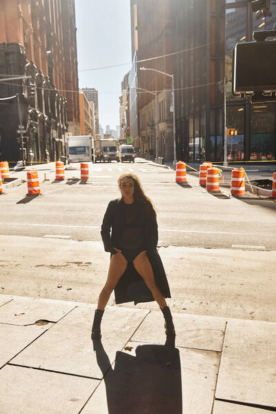 A young woman dances on a New York street, her silhouette framed by the citys towering buildings.