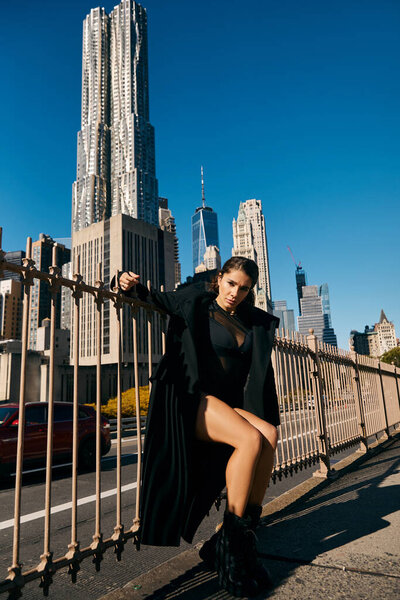 Woman in black coat dances among NYC skyscrapers.