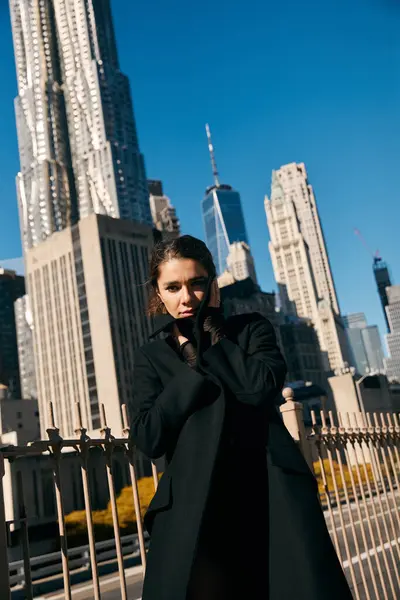 stock image A young woman in a black coat stands on a New York City street.