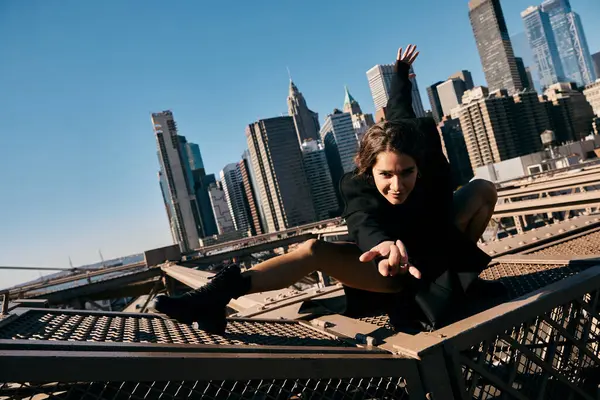 stock image A young woman dances on a bridge in New York City.