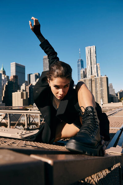 Woman dances on NYC bridge, silhouette against skyscrapers.
