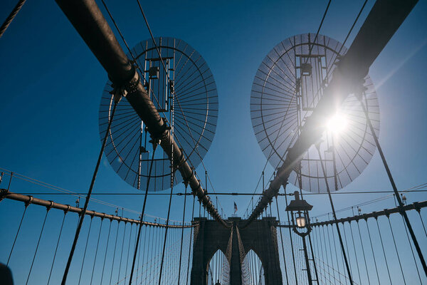 A young woman dances on the Brooklyn Bridge, her silhouette outlined against the bright sun.