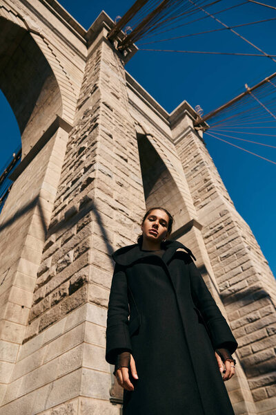 Молодая женщина стоит против возведения моста в Нью-Йорке.