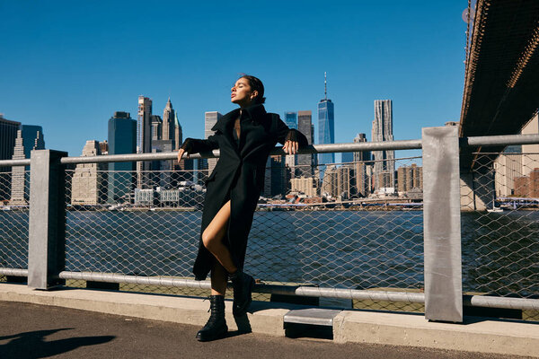 Молодая женщина танцует на улице Нью-Йорка, ее пальто плывет по ветру.