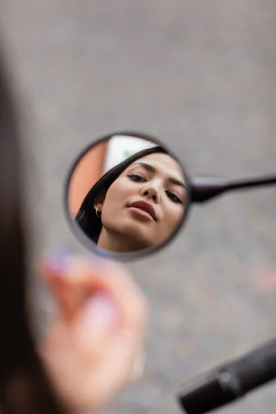 Young brunette woman with makeup looking in mirror on blurred foreground — Stock Photo
