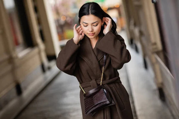 Bella donna in elegante cappotto autunnale con incrocio fissaggio capelli sulla strada della città a Praga — Foto stock