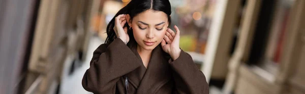 Mulher morena bonita no casaco marrom fixação cabelo ao ar livre em prague, banner — Fotografia de Stock