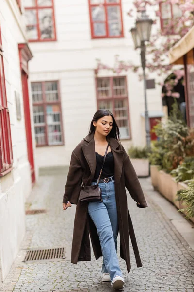 Young and pretty woman in trendy autumn clothes walking along narrow street in prague — Stock Photo