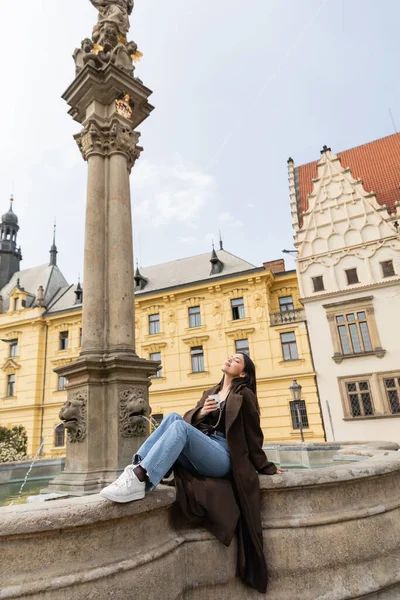 Junge Frau mit Pappbecher in der Nähe der Statue des heiligen Josef und des Brunnens auf dem Karlsmarkt in Prag — Stockfoto