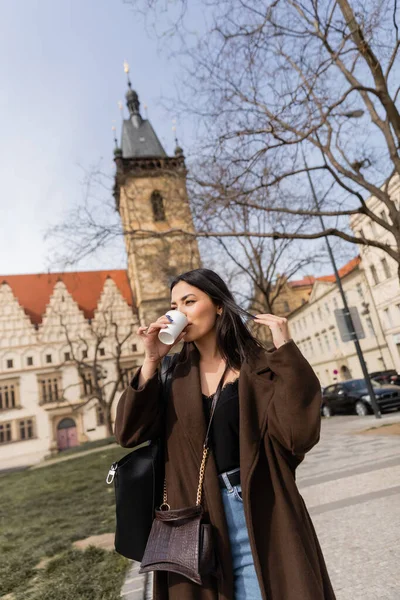 Stilvolle junge Frau trinkt Kaffee zum Mitnehmen auf der Straße in Prag — Stockfoto