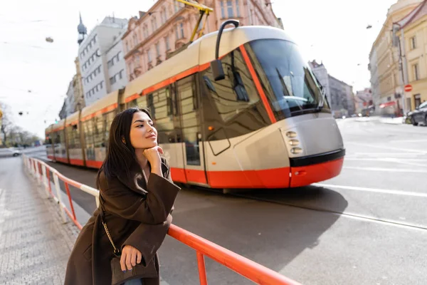 Stylish traveler standing near blurred tram on street in Prague — Stock Photo