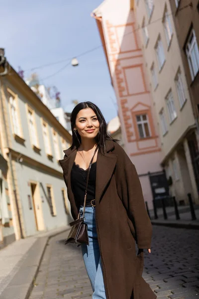 Весела жінка в коричневому пальто, що дивиться на вулицю з сонячним світлом у Празі. — Stock Photo
