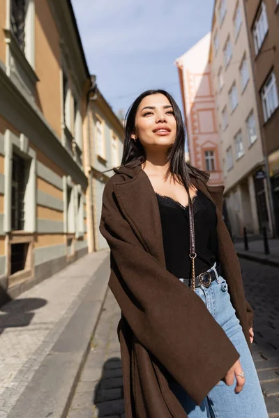 Pretty brunette woman in coat looking away on street in Prague — Stock Photo