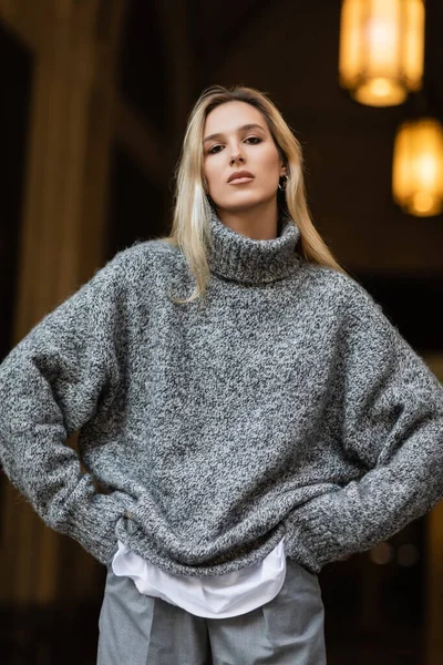 Портрет молодой женщины в стильном сером свитере, смотрящей в камеру во время позирования в Нью-Йорке — стоковое фото