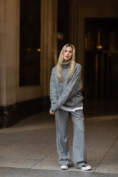 Полная длина красивой и стильной женщины в сером наряде, стоящей на улице Нью-Йорка — стоковое фото
