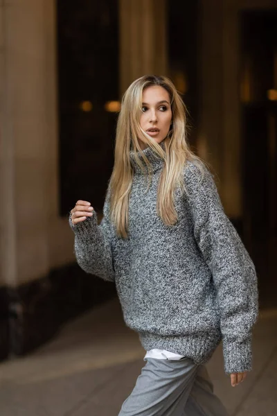 Стильная женщина в сером вязаном свитере зимой смотрит на улицу Нью-Йорка — стоковое фото