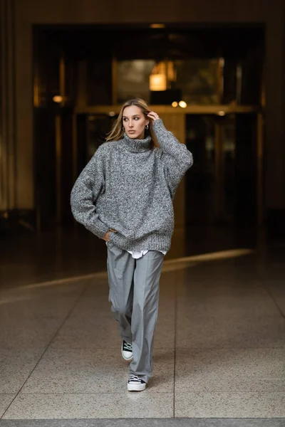 Longueur pleine de jeune femme élégante en tenue grise marchant la main dans la poche sur la rue de New York en hiver — Photo de stock