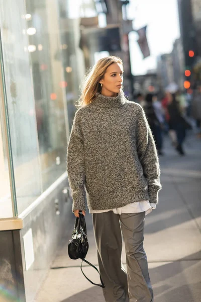Junge und stilvolle Frau im grauen Outfit mit trendiger Handtasche auf der Straße von New York — Stockfoto