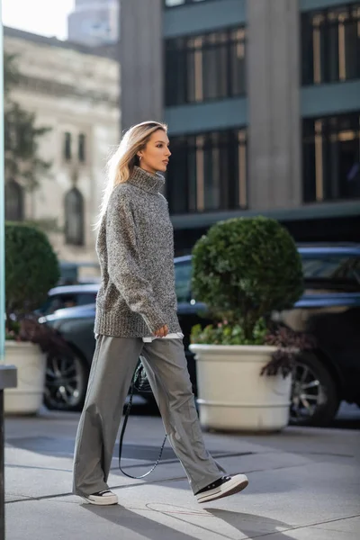 Full length of young woman with blonde hair walking in trendy winter outfit in New York — Stock Photo