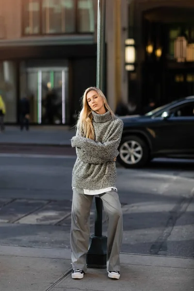Longitud completa de la mujer joven con estilo en traje de invierno de moda posando cerca de poste de la calle en Nueva York - foto de stock