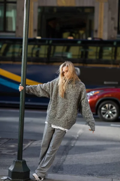 Full length of stylish young woman in grey winter outfit posing near street pole in New York city — Stock Photo