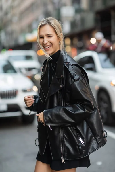 Portrait of blonde woman in stylish leather jacket laughing on urban street in New York — Stock Photo