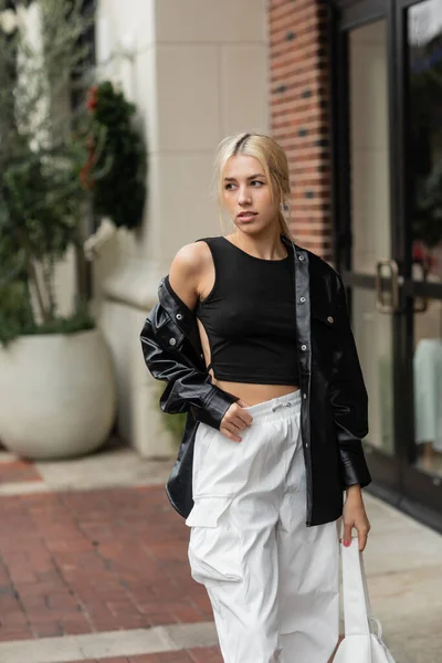 Junge blonde Frau in Lederjacke posiert mit Handtasche auf der Straße in Miami — Stockfoto