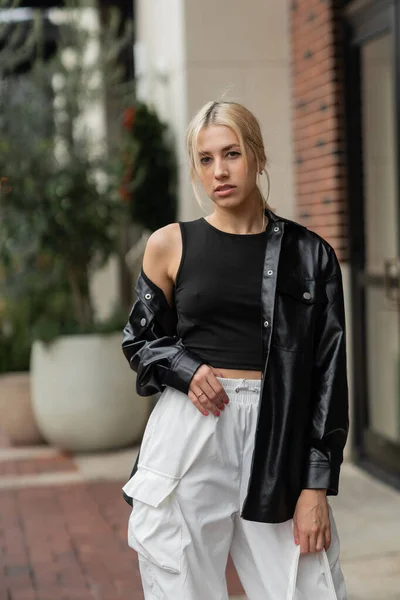 Junge blonde Frau in Lederjacke posiert mit Handtasche in Miami — Stockfoto