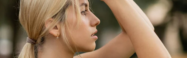Vista lateral de la mujer joven con el pelo rubio mirando hacia afuera, pancarta - foto de stock