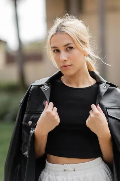 Ritratto di giovane donna bionda in giacca di pelle nera guardando la macchina fotografica — Foto stock