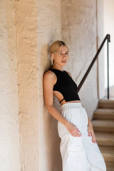 Blonde Frau in stylischem Outfit steht an Wand eines modernen Hauses in Miami — Stockfoto