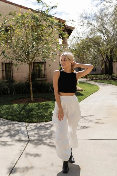 Pleine longueur de femme gaie dans des vêtements à la mode debout près de la maison moderne à Miami — Photo de stock