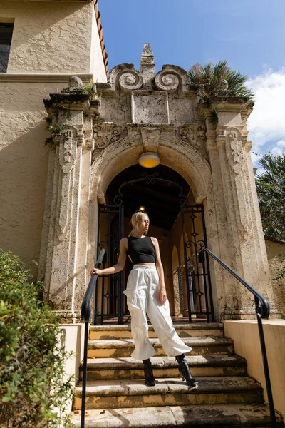 Повний зріст білявки, що стоїть біля вхідних дверей середземноморського будинку в Маямі. — Stock Photo