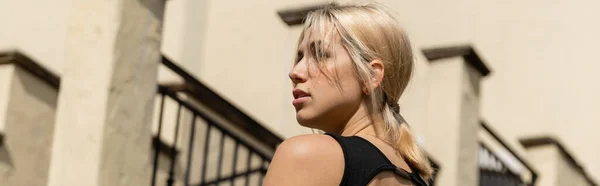 Blonde young woman in tank top standing near building in Miami, banner — Stock Photo